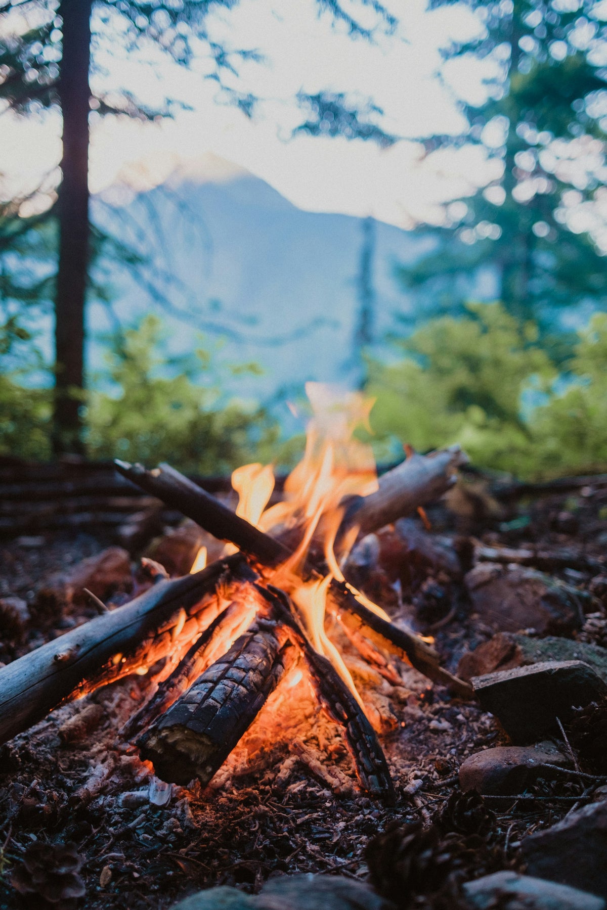 A campfire glowing against mountain scenery at sunset